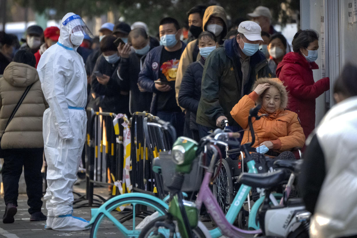 People wearing face masks wait for COVID-19 tests at a coronavirus testing site in Beijing, Thursday, Nov. 17, 2022. Chinese authorities faced more public anger Thursday after a second child's death was blamed on overzealous anti-virus enforcement, adding to frustration at controls that are confining millions of people to their homes and sparked fights with health workers. (AP Photo/Mark Schiefelbein)