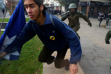 A demonstrator runs away from a riot policeman during an unauthorized march called by secondary students to protest against government education reforms in Santiago, Chile, May 26, 2016. REUTERS/Ivan Alvarado