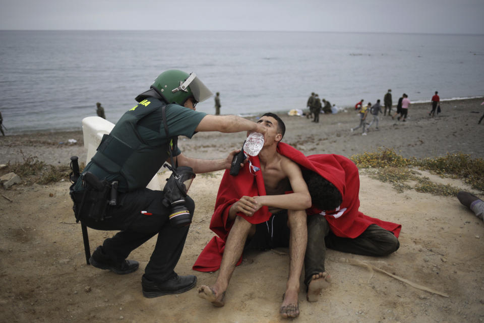 A man from Morocco is assisted by a Guardia Civil officer as he arrives swimming at the Spanish enclave of Ceuta, on Tuesday, May 18, 2021. About 8,000 people have streamed into the Spanish city of Ceuta from Morocco in the past two days in an unprecedented influx of migrants, most of them swimming across the border to reach the Spanish enclave in North Africa. (AP Photo/Javier Fergo)