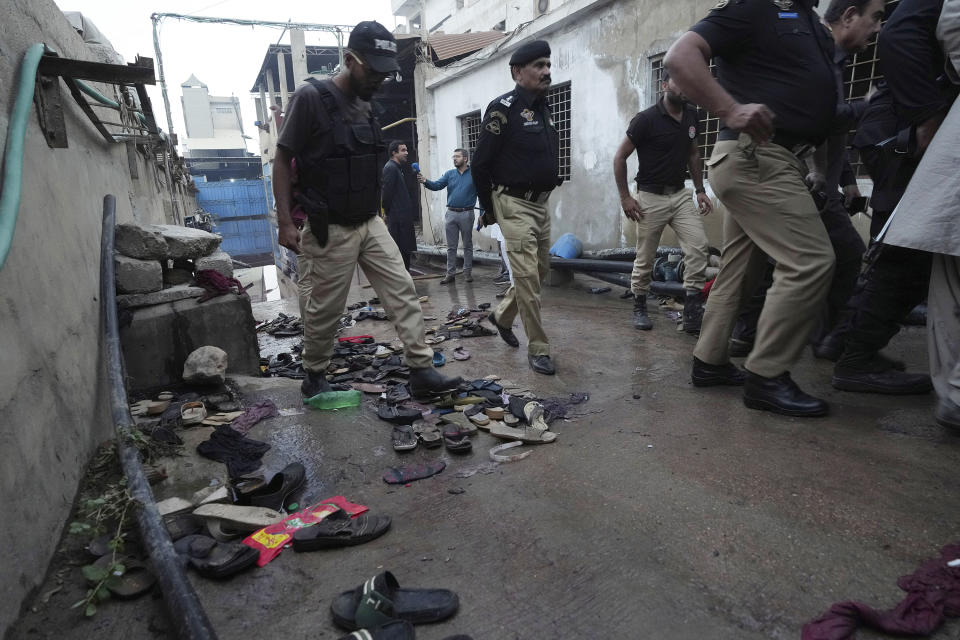 Police officers examine the site of stampede, in Karachi, Pakistan, Friday, March 31, 2023. Several people were killed in the deadly stampede at a Ramadan food distribution center outside a factory in Pakistan's southern port city of Karachi, police and rescue officials said. (AP Photo/Fareed Khan)