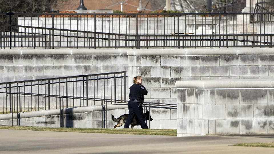 A Capitol Police officer and her ordinance sniffing dog walk along the Carroll Gartin Justice Building in Jackson, Miss., Thursday, Jan. 4, 2024, as officials deal with a second consecutive day of bomb threats to the Mississippi State Capitol and the justice building which houses the state supreme and appellate courts. (AP Photo/Rogelio V. Solis)