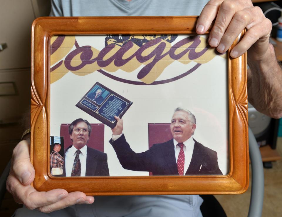 Kerry Baker holds a photograph of himself, left, with Cardinal Mooney's coach John Heath, right, taken in 1985. Heath was the first inductee in the Cardinal Mooney Sports Hall of Fame.