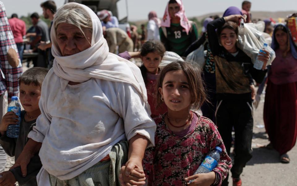 Displaced Yazidis pass flee from Mount Sinjar after it was invaded by Islamic State fighters - Sam Tarling for The Telegraph