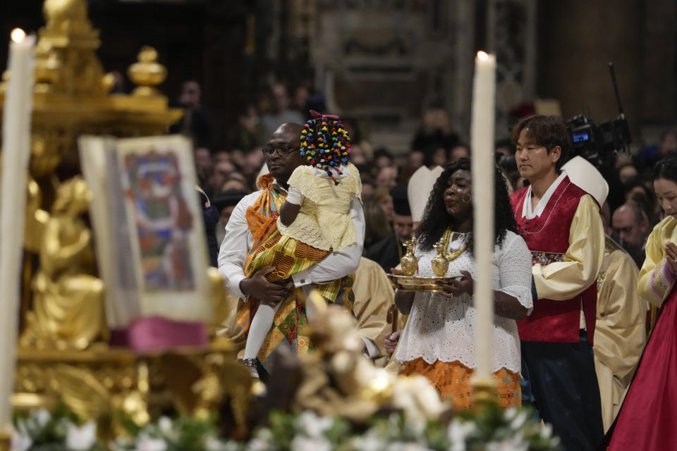 Families brings gifts to the altar as Pope Francis presides over Christmas eve Mass, at St. Peter's Basilica at the Vatican, Sunday Dec. 24, 2023. (AP Photo/Gregorio Borgia)