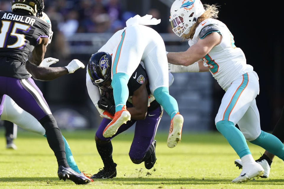 Baltimore Ravens running back Justice Hill, bottom, lifts up Miami Dolphins linebacker Duke Riley, top, during the first half of an NFL football game in Baltimore, Sunday, Dec. 31, 2023. (AP Photo/Matt Rourke)