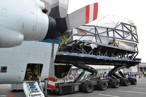 Shrink-wrapped in plastic, the space shuttle crew compartment from NASA Johnson Space Center’s Full Fuselage Trainer (FFT) is offload from the space agency’s Super Guppy cargo plane onto a military transport at The Museum of Flight in Seattle,