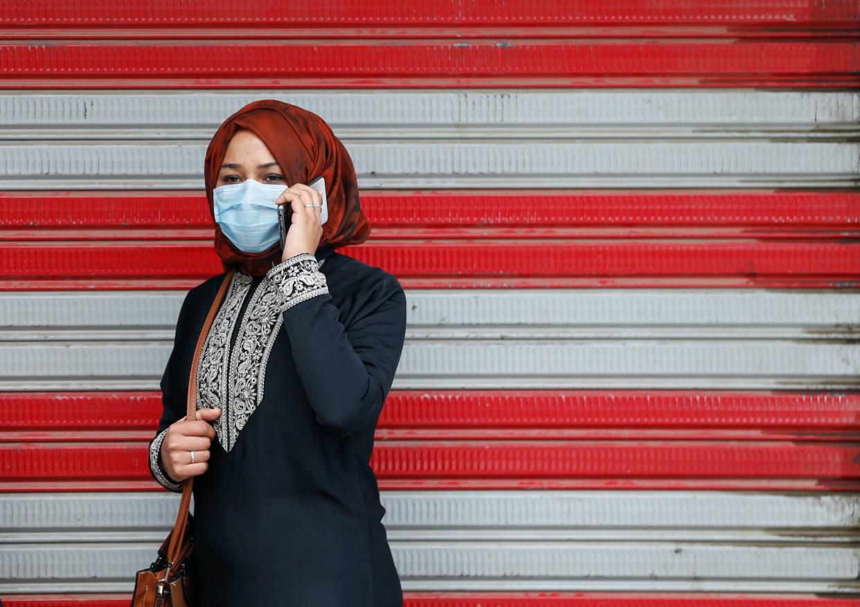 woman mobile cell phone coronavirus covid 19 surgical face mask kabul afghanistan red white background 2020 03 29T095012Z_1762391908_RC2LTF96UYPF_RTRMADP_3_HEALTH CORONAVIRUS AFGHANISTAN.JPG