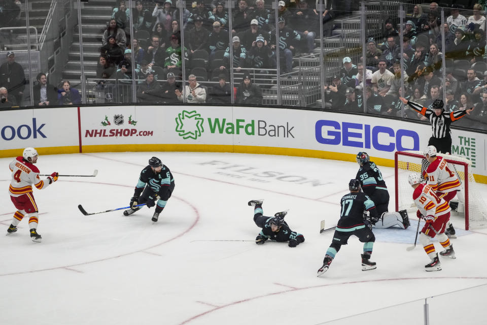 Calgary Flames defenseman Rasmus Andersson (4) shoots and scores the winning goal in front of Seattle Kraken defenseman Adam Larsson (6) and center Alex Wennberg (21) during overtime in an NHL hockey game Monday, Nov. 20, 2023, in Seattle. The Flames won 4-3 in overtime. (AP Photo/Lindsey Wasson)