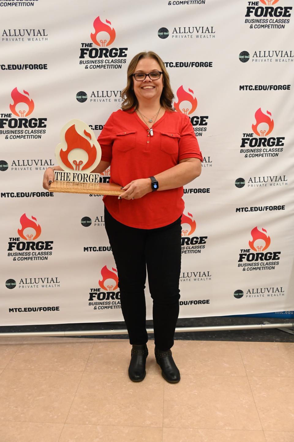 Elaine Strine holds her trophy for winning the Alluvial Private Wealth Forge competition for her business, C.L. Gregory Nonprofit Music Academy.