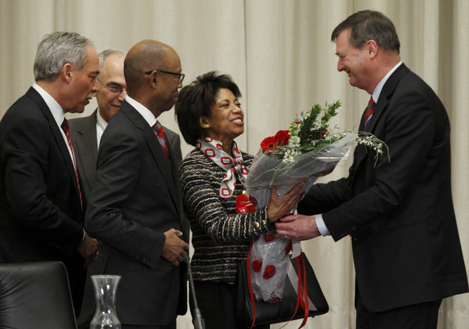 Ohio State University board trustee Jeffery Wadsworth, right, presents Brenda Drake, second from right, with flowers as her husband Dr. Michael Drake, third from right, looks on with board chair Robert Schottenstein, left, and interim university president Joseph Alutto after Dr. Drake was voted in as the incoming president of the university during a board meeting at the university Wednesday, Jan. 30, 2014. (AP Photo/Paul Vernon)