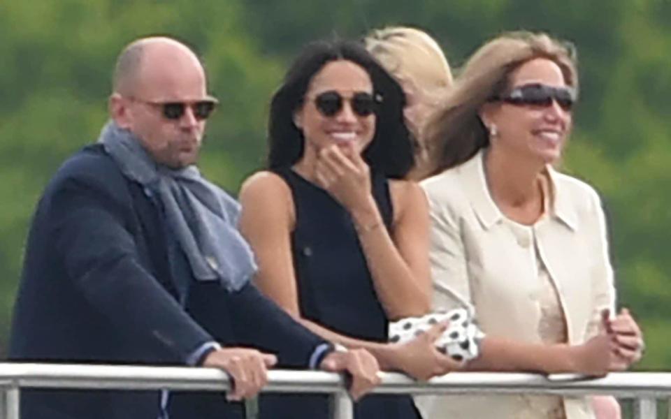 Ms Markle, centre, was all smiles as she watched the action with friends - James Whatling Photography