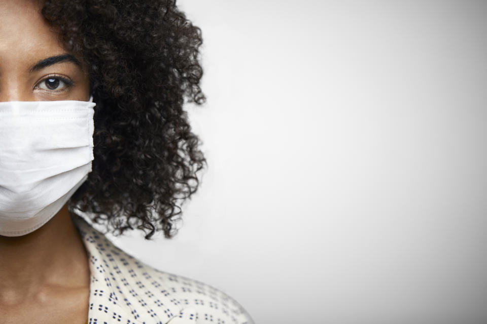 Closeup portrait of a young African American woman with face mask on the studio against white background.