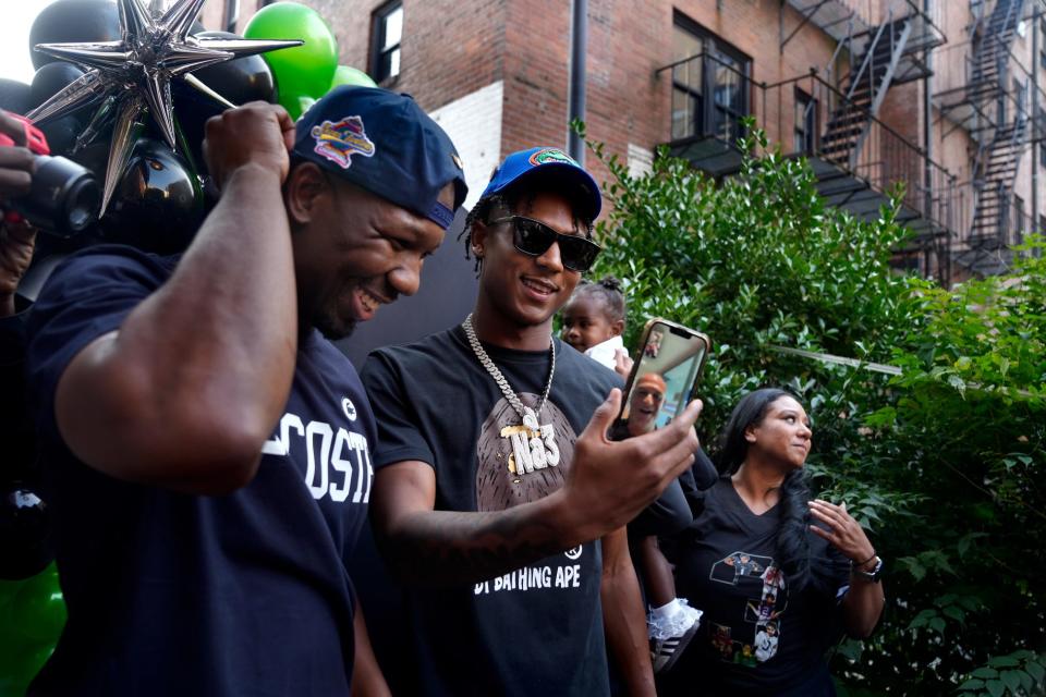 Former RI high schooler, Naeshaun Montgomery (center) holds up his phone while talking with the coach of his new college football team, Billy Napier, after he commits to play football with the University of Florida Gators on Sunday evening, August 25, 2024. Left is his dad Kashif Montgomery and to the right is sister Chloe and mom Natasha Alvarez.