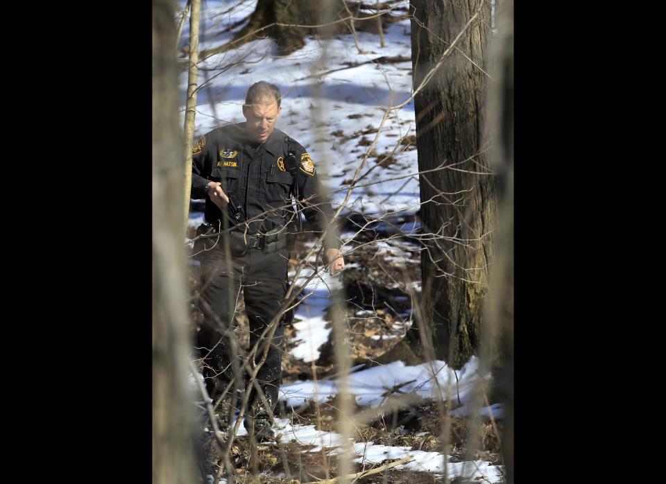 A deputy sheriff searches a wooded area with his gun drawn several miles from Chardon High School in Chardon, Ohio, Monday, Feb. 27, 2012. A gunman opened fire inside the high school cafeteria at the start of the school day Monday, killing three students and wounding two others, authorities said. A suspect believed to be a student was arrested a short distance away. (AP Photo/Tony Dejak)