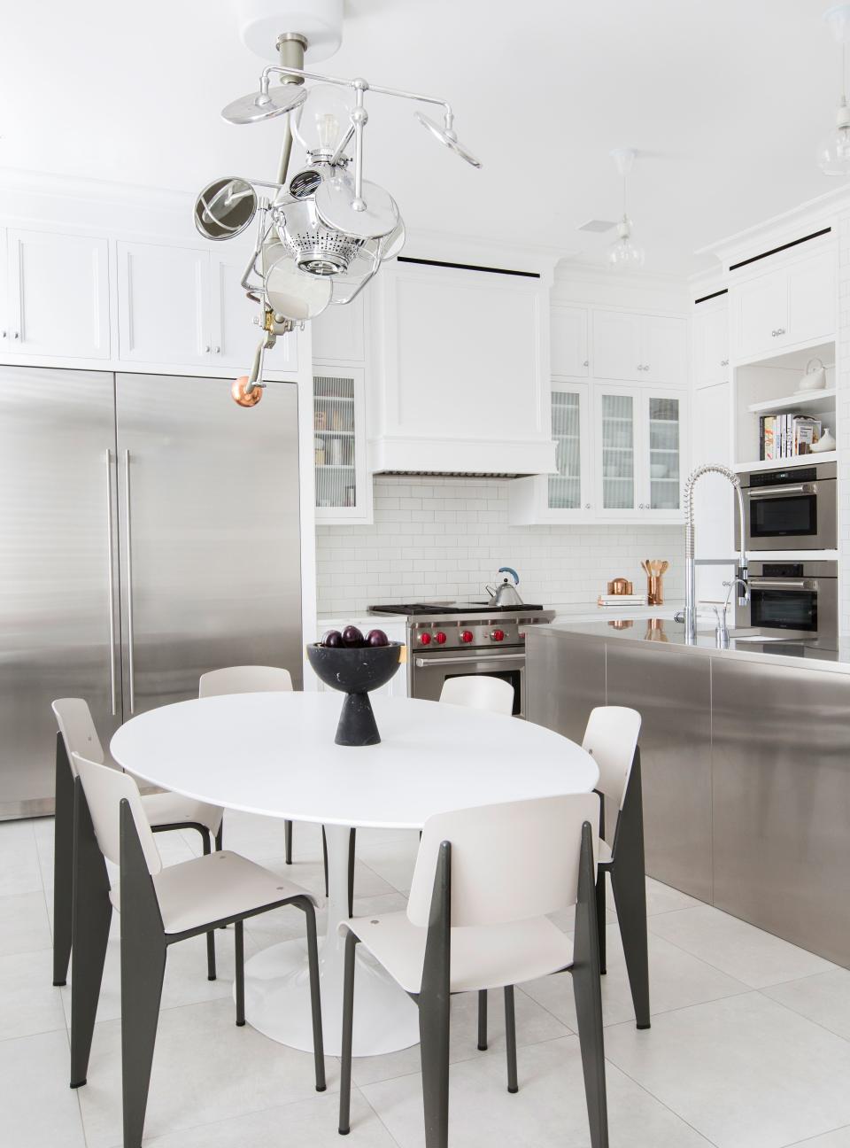 An abundance of stainless steel, seen in the kitchen island and several appliances, gives the kitchen a “super utilitarian feeling,” says Grehl. Midcentury furnishings both complement and counterbalance the sleek look.