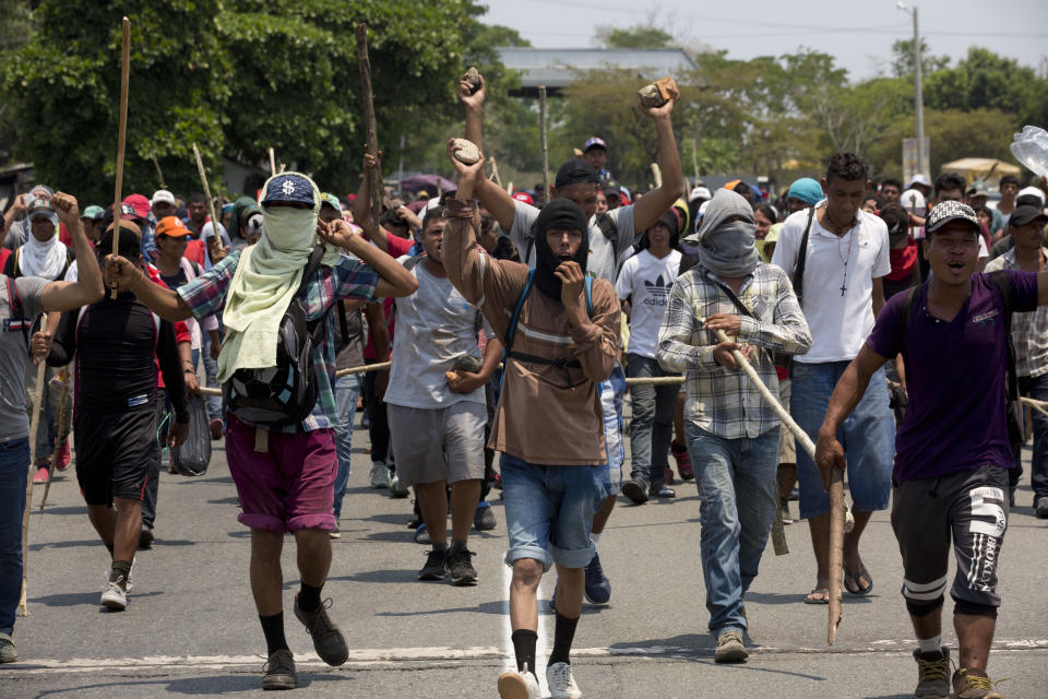 After Mexican immigration agents detained some Central American migrants on the highway, other migrants from the group carry wooden sticks and stones for self-defense as they continue their trek to Pijijiapan, Mexico, Monday, April 22, 2019. Mexican police and immigration agents detained hundreds of migrants Monday in the largest single raid on a migrant caravan since the groups started moving through Mexico last year. (AP Photo/Moises Castillo)