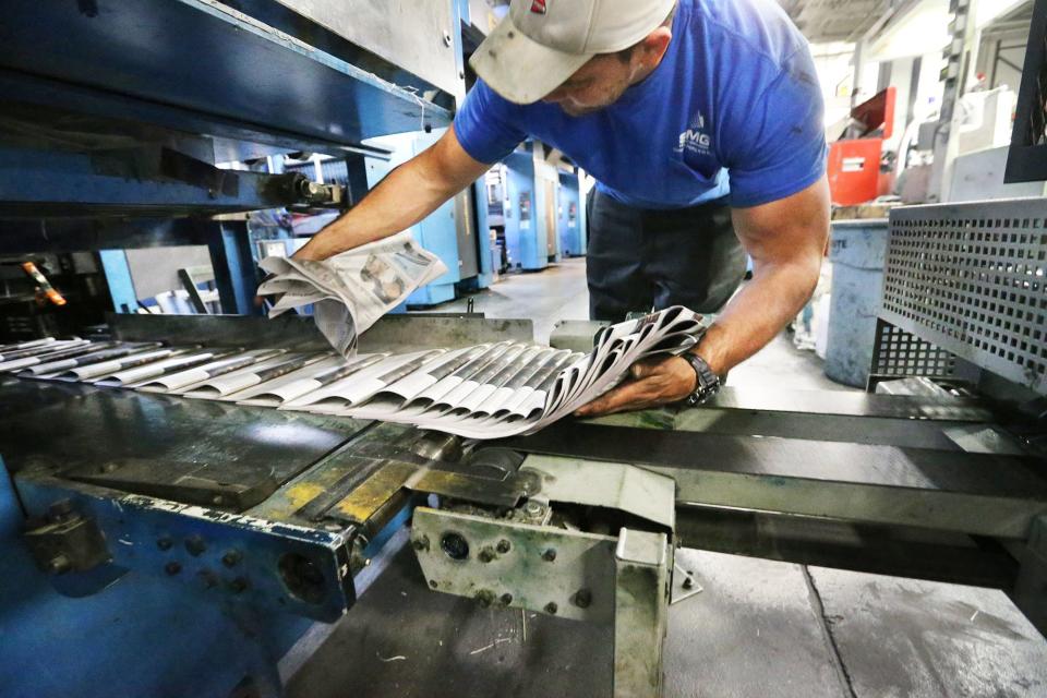 Press operator Andy Harbison scoops up Portsmouth Herald newspapers during the last time papers will be printed at Seacoast Media Group in Portsmouth Sunday, March 19, 2023.