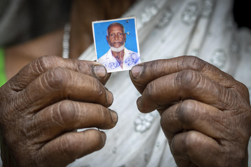 Subur Banoo, 60, wife of late Faizul Ali, shows a photograph of husband outside her house in Bahari, north eastern Assam state, India, April 16, 2023. Ali was sent to a detention center after being declared a “foreigner” in late 2015, and was released on bail in 2019. He died in March, leaving behind his wife, a mentally ill son, two daughter-in-laws and their children. They all live in a single room house made of corrugated tin in this Muslim majority village. All have been declared “foreigners.” (AP Photo/Anupam Nath)