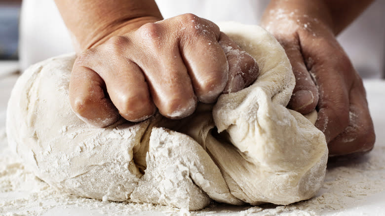 Person kneading bread dough on a floured surface