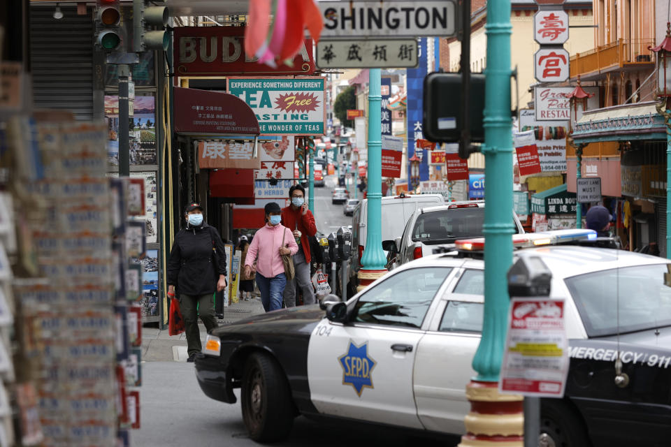 SAN FRANCISCO, CALIFORNIA - MARCH 17: Pedestrians cross the street by a San Francisco police car where an officer is standing guard in Chinatown on March 17, 2021 in San Francisco, California. The San Francisco police have stepped up patrols in Asian neighborhoods in the wake of a series of shootings at spas in the Atlanta area that left eight people dead, including six Asian women. The main suspect, Robert Aaron Long, 21, has been taken into custody. The San Francisco Bay Area is also seeing an increase in violence against the Asian community. (Photo by Justin Sullivan/Getty Images)