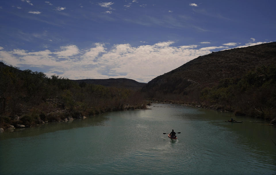 A paddler floats along the Devil's River, Friday, Feb. 17, 2023, near Del Rio, Texas. Some landowners along the Devil's River argue that proposed wind turbines would kill birds, bats and disrupt monarch butterflies migrating to Mexico and impact ecotourism, a main source of income for many. (AP Photo/Eric Gay)