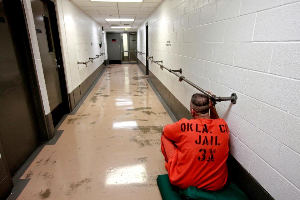 An inmate is handcuffed to a rail July 5, 2011, in the hallway at the Oklahoma County jail.