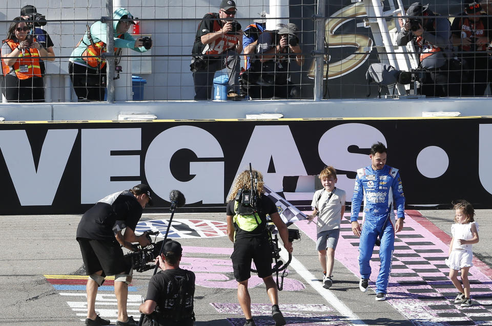 NASCAR Cup Series driver Kyle Larson picks up the checkered flag with his son Owen and daughter Audrey after winning a NASCAR Cup Series auto race, Sunday, Oct. 15, 2023, in Las Vegas. (AP Photo/Steve Marcus)