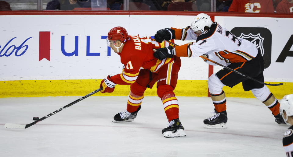 Anaheim Ducks forward Mason McTavish, right, checks Calgary Flames forward Mikael Backlund during second-period NHL hockey game action in Calgary, Alberta, Sunday, April 2, 2023. (Jeff McIntosh/The Canadian Press via AP)