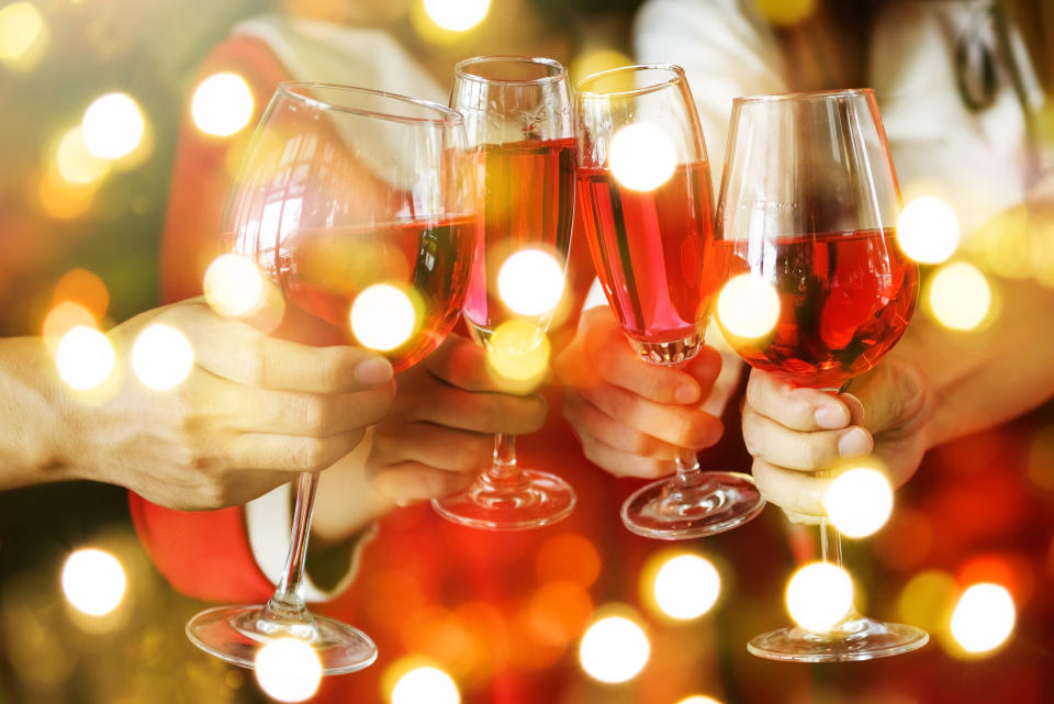 Group of hands toasting glasses of red wine for Christmas or xmas celebrating party. Closeup photo with bokeh light for New year holiday celebration.