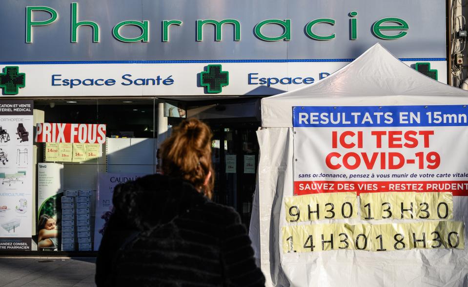A woman waits in front of a pharmacy with a sign reading "Results in 15 minutes, here Covid-19 test, save lives, stay careful" in Le Perreux-sur-Marne, eastern Paris, on November 18, 2020. (Photo by BERTRAND GUAY / AFP) (Photo by BERTRAND GUAY/AFP via Getty Images)