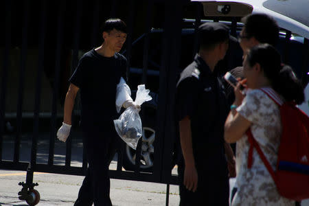 A security personnel carries a plastic bag as he walks past the U.S. embassy in Beijing, China July 26, 2018. REUTERS/Thomas Peter