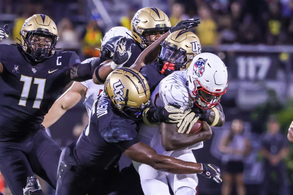 Louisville Cardinals quarterback Malik Cunningham is tackled by UCF defenders during the first quarter.