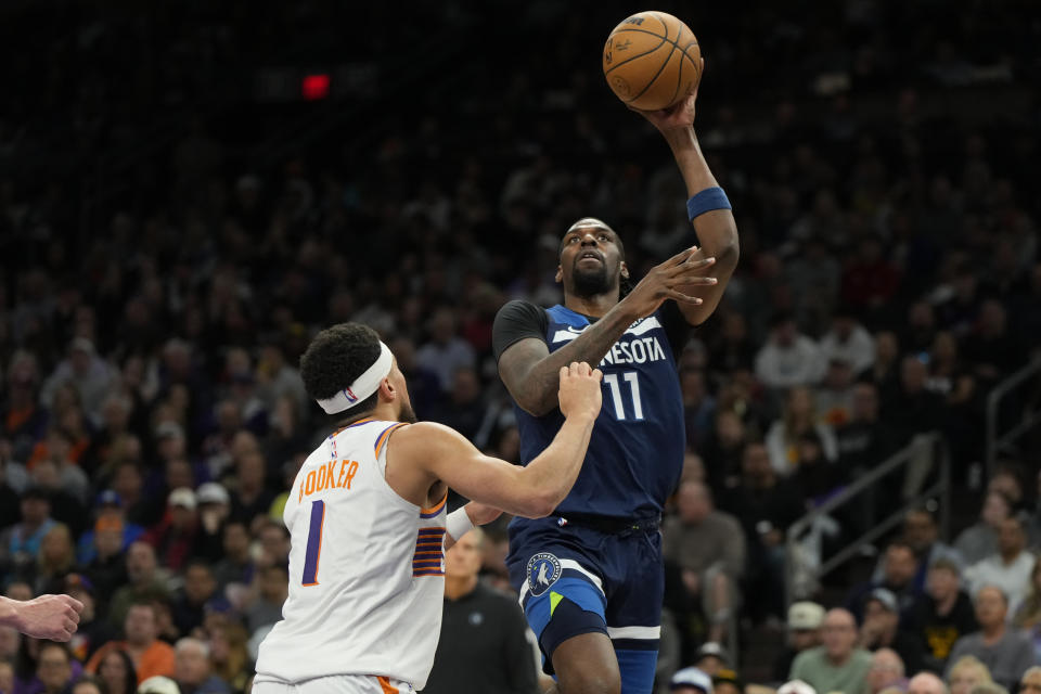 Minnesota Timberwolves center Naz Reid shoots over Phoenix Suns guard Devin Booker during the second half of an NBA basketball game Friday, April 5, 2024, in Phoenix. (AP Photo/Rick Scuteri)