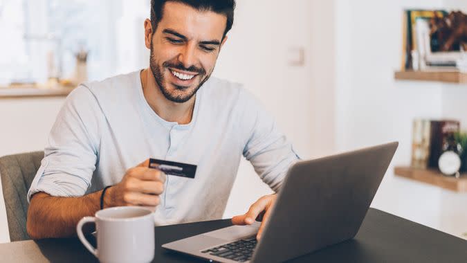 Young handsome man shopping online with credit card and laptop at home.