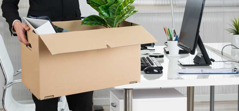 Businessman carrying cardboard box after being fired.