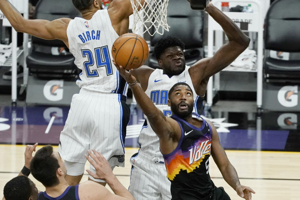 Phoenix Suns guard E'Twaun Moore (55) drives past Orlando Magic center Khem Birch (24) and center Mo Bamba during the first half of an NBA basketball game Sunday, Feb. 14, 2021, in Phoenix. (AP Photo/Rick Scuteri)