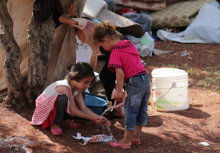 A displaced Syrian girl from the al-Ahmed family washes her hands in an olive grove in the town of al Atmeh, Idlib province, Syria, May 16, 2019. REUTERS/Khalil Ashawi