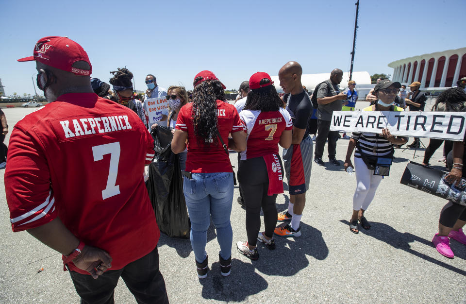 INGLEWOOD, CA-june 11, 2020: Katie Fuller, 74, of Inglewood, right, holding sign, joins other protesters in the Forum parking lot, across the street from Sofi Stadium in Inglewood, background, demanding that the NFL apologize to former NFL quarterback Colin Kaepernick. The protesters also took a knee for 8 minutes and 46 seconds to remember George Floyd who who held down by a police officer with a knee to his neck for the same time and died as a result. (Mel Melcon/Los Angeles Times via Getty Images)