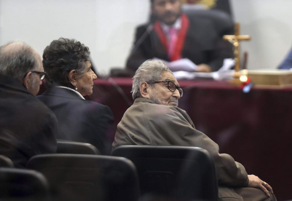 FILE - In this Sept. 11, 2018 file photo taken through a window, Abimael Guzman, founder and leader of the Shining Path guerrilla movement, looks at his lawyer while siting with his partner Elena Iparraguirre, during the sentencing phase of their trial at a naval base in Callao, Peru. The Peruvian government reported Saturday, Sept. 11, 2021, that Guzman died after an illness. (AP Photo/Martin Mejia, File)