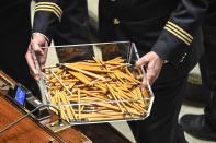 A parliament clerk carries used pencils in the Italian parliament, in Rome, Wednesday, Jan. 26, 2022. The first two rounds of voting in Italy's Parliament for the country's next president yielded an avalanche of blank ballots, as lawmakers and special regional electors failed to deliver a winner amid a political stalemate. (Alberto Pizzoli/Pool photo via AP)