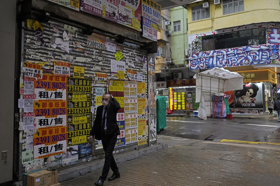 A man wearing a protective mask walks past a closed shop covered with advertisements for rentals and sales in Mongkok district in Hong Kong, Thursday, Feb. 17, 2022. Hong Kong on Thursday reported 6,116 new coronavirus infections, as the city’s hospitals reached 90% capacity and quarantine facilities are at their limit, authorities said. (AP Photo/Kin Cheung)