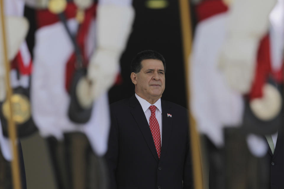 FILE - In this Aug. 21, 2017 file photo, then Paraguay's President Horacio Cartes stands for the playing of his country's national anthem during a welcome ceremony at the Planalto Presidential Palace, in Brasilia, Brazil. Brazilian police are seeking the arrest of Cartes as part of an investigation into kickbacks and money laundering. Federal prosecutors said Tuesday, Nov. 19, 2019, that Cartes is among 20 suspects being sought by Brazilian police. (AP Photo/Eraldo Peres, File)