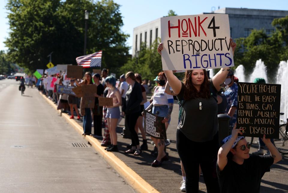 Abortion rights demonstrators wave signs at the Oregon State Capitol in Salem Wednesday to protest the U.S. Supreme Court decision to overturn federal abortion protections.