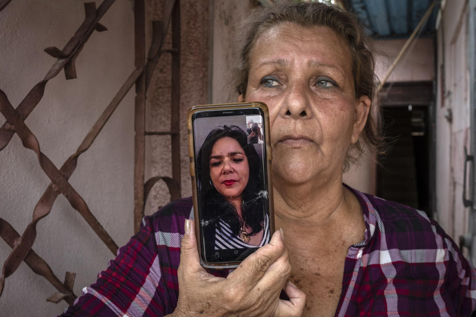 Yanelis Leon speaks by videoconference from the U.S. during an interview The as her mother Natacha Gonzalez, who cares for her two children, holds the phone at the door of her home in Cienfuegos, Cuba, Thursday, May 19, 2022. Separated families between Cuba and the U.S. see hope in the measures announced by the administration of President Joe Biden, but the long wait of years and a web of political interests also makes them skeptical. (AP Photo/Ramon Espinosa)