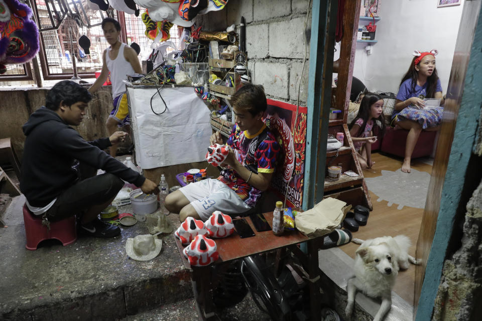 Therry Sicat, center, finishes paint on miniature lion heads as they seek other ways to earn a living at a creekside slum at Manila's Chinatown, Binondo Philippines on Feb. 3, 2021. The Dragon and Lion dancers won't be performing this year after the Manila city government has banned the dragon dance, street parties, stage shows or any other similar activities during celebrations for the Chinese New Year due to COVID-19 restrictions leaving several businesses without income as the country grapples to start vaccination this month. (AP Photo/Aaron Favila)