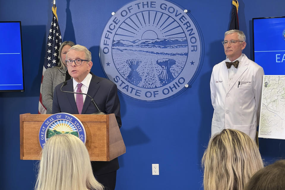 Ohio's Republican governor, Mike DeWine, at the microphone in front of a large seal reading: Office of the Governor, State of Ohio. His desk has a seal reading: Great Seat of the State of Ohio.