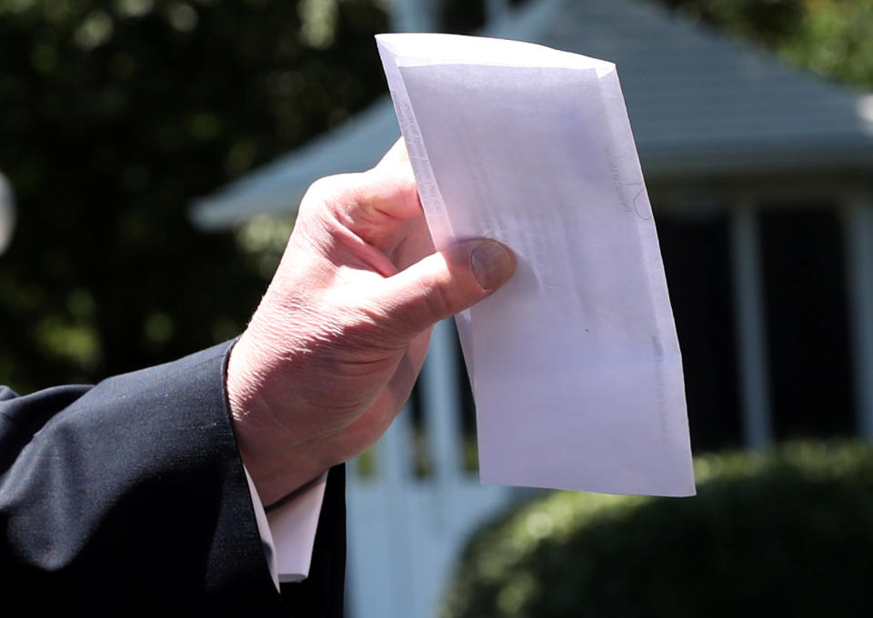 U.S. President Donald Trump holds up a copy of a deal with Mexico on immigration and trade as he speaks to the news media prior to departing for travel to Iowa from the White House in Washington, U.S., June 11, 2019. The document says the U.S.-Mexico migrant agreement reached last week includes a regional asylum plan and that Mexico agreed to examine its laws and potentially change them in order to implement the deal.  REUTERS/Leah Millis