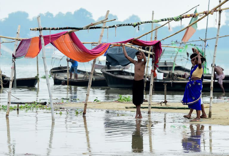 Los vendedores trasladan sus refugios improvisados ​​de las orillas del río Ganges a medida que aumenta el nivel del agua