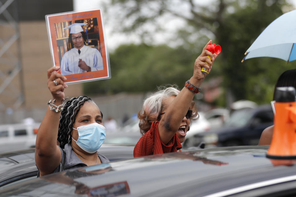 Micheal Pitts, left, and Deborah Bibbins, mother of graduate Cameron Magee, cheer him as the New Orleans Charter Science and Math High School class of 2020 holds a drive-in graduation ceremony as a result of the COVID-19 pandemic, outside Delgado Community College in New Orleans, Wednesday, May 27, 2020. Students and family got out of their cars to receive diplomas one by one, and then held a parade of cars through city streets. (AP Photo/Gerald Herbert)