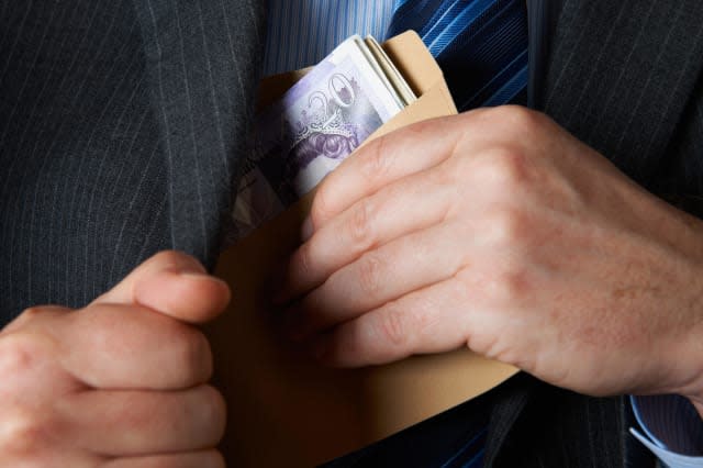 Businessman Putting Envelope Filled With Sterling In Jacket Pocket